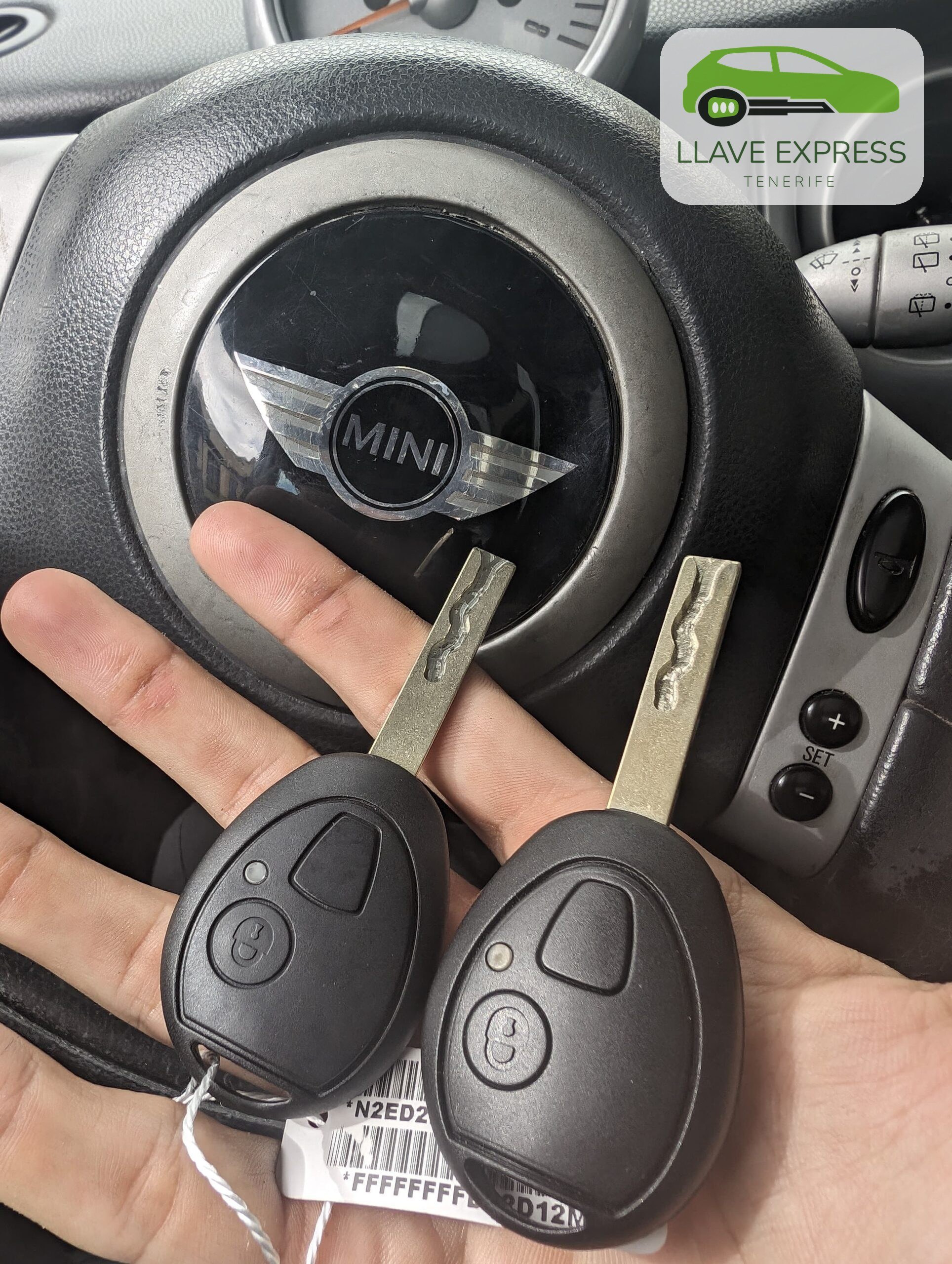 Llaves MINI — fotografía original Dos llaves sostenidas frente al volante de un MINI.